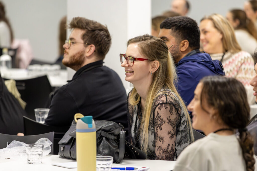 Image of woman sitting amongst other INSIGHT conference attendees, laughing